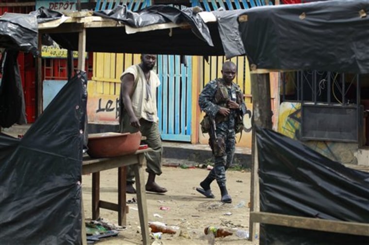 Soldiers loyal to Alassane Ouattara walk past deserted market stalls and closed businesses in Abidjan, Ivory Coast, on Thursday. 